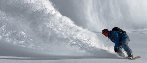 Snowboarder hitting a huge powder slash after hitting the cornice at Tamarack Resort in Idaho