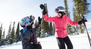 A mom and a kid high fiving after skiing Tamarack Resort in Idaho